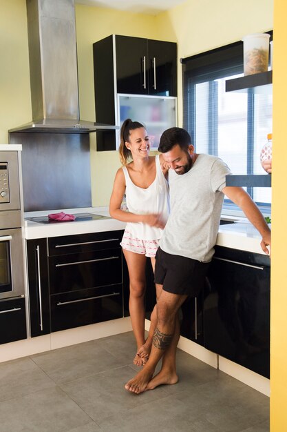 Feliz pareja de pie en la cocina moderna