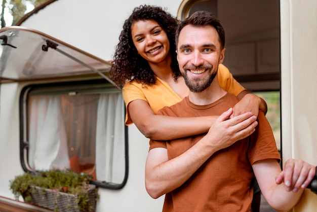 Foto gratuita feliz pareja de pie delante de la autocaravana