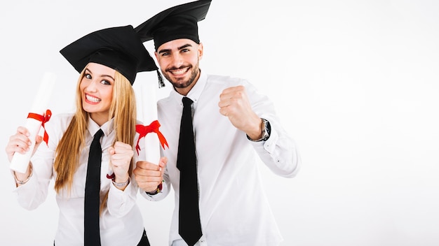 Feliz pareja de pie con diplomas