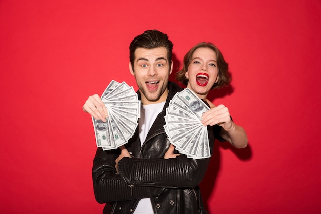 Foto gratuita feliz pareja punk joven posando con dinero