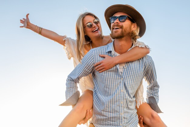 Feliz pareja riendo viajando en verano por mar, hombre y mujer con gafas de sol