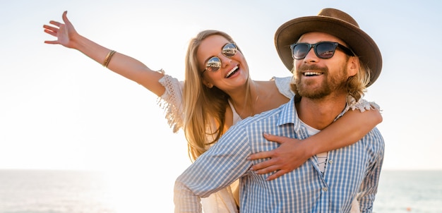 Feliz pareja riendo viajando en verano por mar, hombre y mujer con gafas de sol