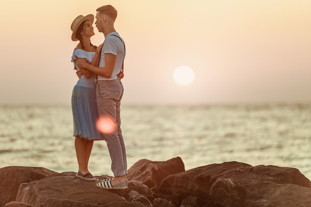 Feliz pareja romántica joven relajante en la playa y viendo el atardecer