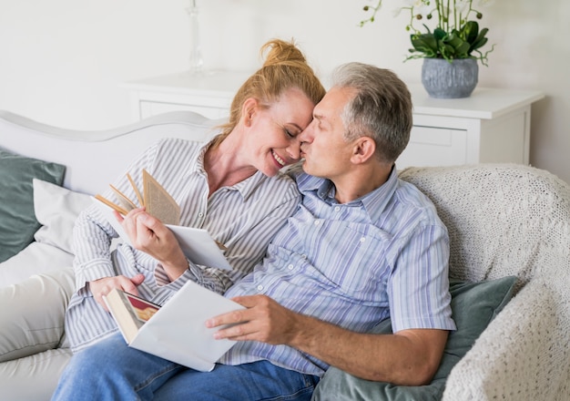 Feliz pareja senior con libros en un sofá