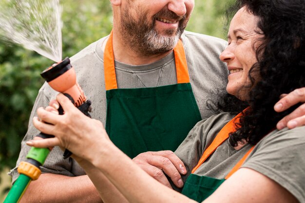 Feliz pareja senior con manguera de agua