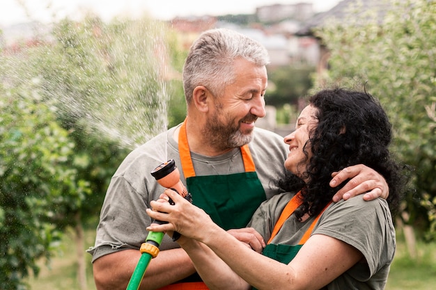 Feliz pareja senior con manguera de agua