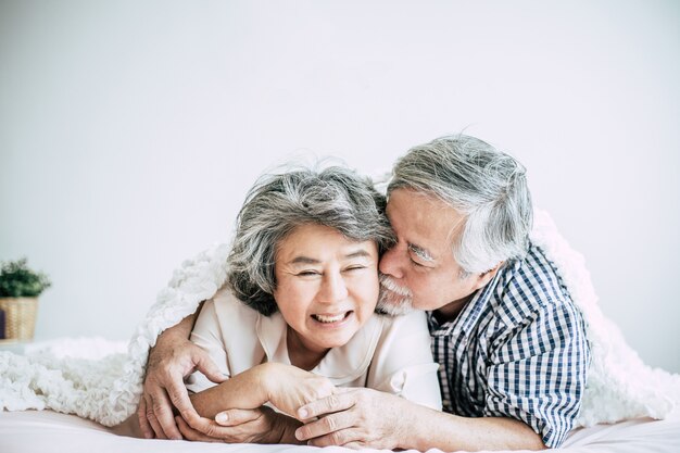 Feliz pareja senior riendo en el dormitorio