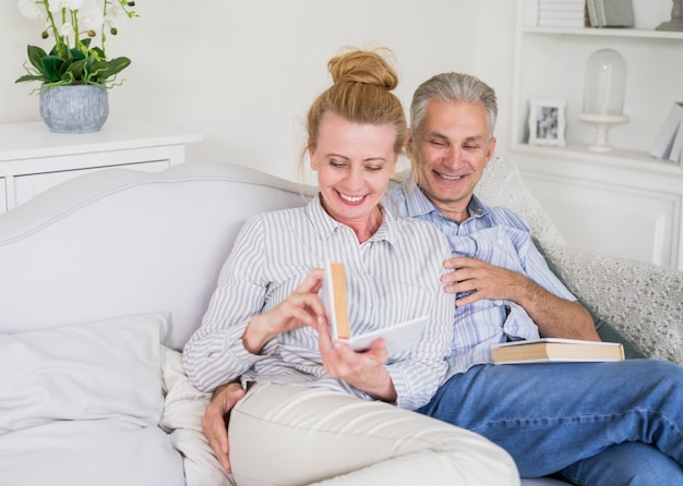 Feliz pareja senior sentado en el sofá con libros