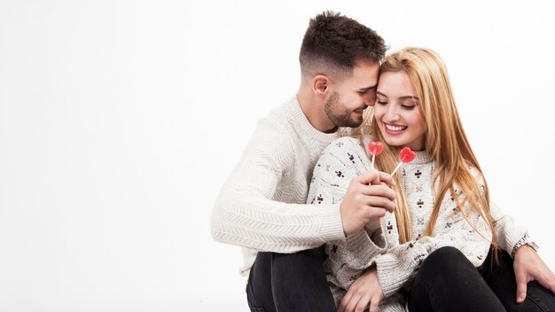 Feliz pareja sentada con piruletas