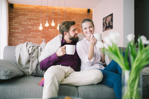 Feliz pareja sentada con tazas