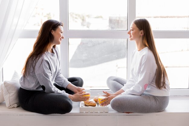 Feliz pareja sentada en la ventana con desayuno