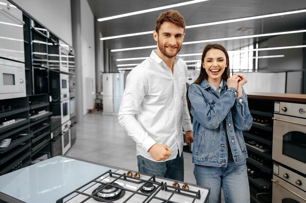 Feliz pareja sonriente acaba de comprar nuevos electrodomésticos en hipermercado