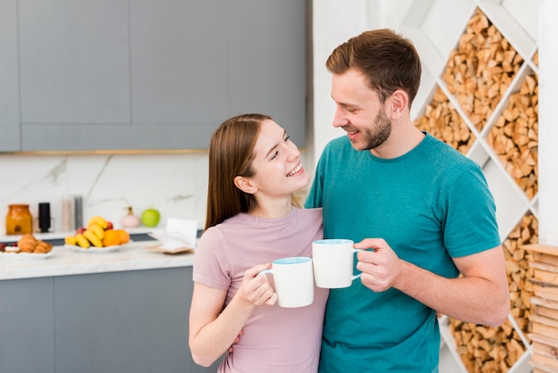 Feliz pareja sosteniendo copas en la cocina