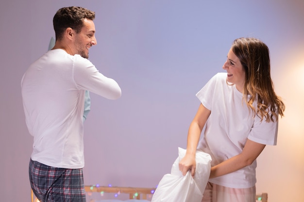 Foto gratuita feliz pareja teniendo una pelea de almohadas