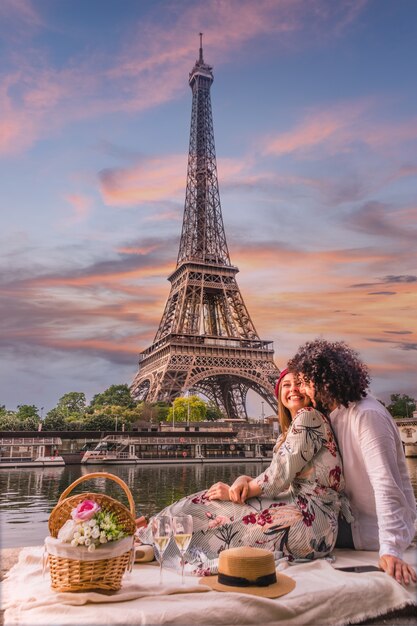 Feliz pareja tomando vino con la vista de la Torre Eiffel