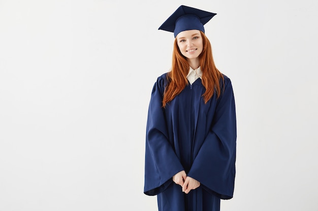 Feliz pelirroja mujer graduada sonriendo.