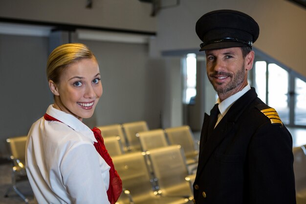 Feliz piloto y azafata de pie en la terminal del aeropuerto