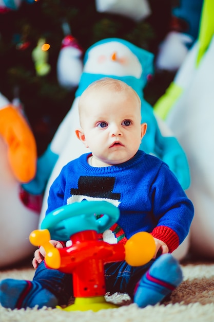 Foto gratuita feliz poco niño cerca de muñeco de nieve de juguete en el estudio