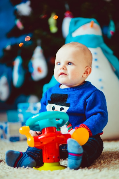 feliz poco niño cerca de muñeco de nieve de juguete en el estudio