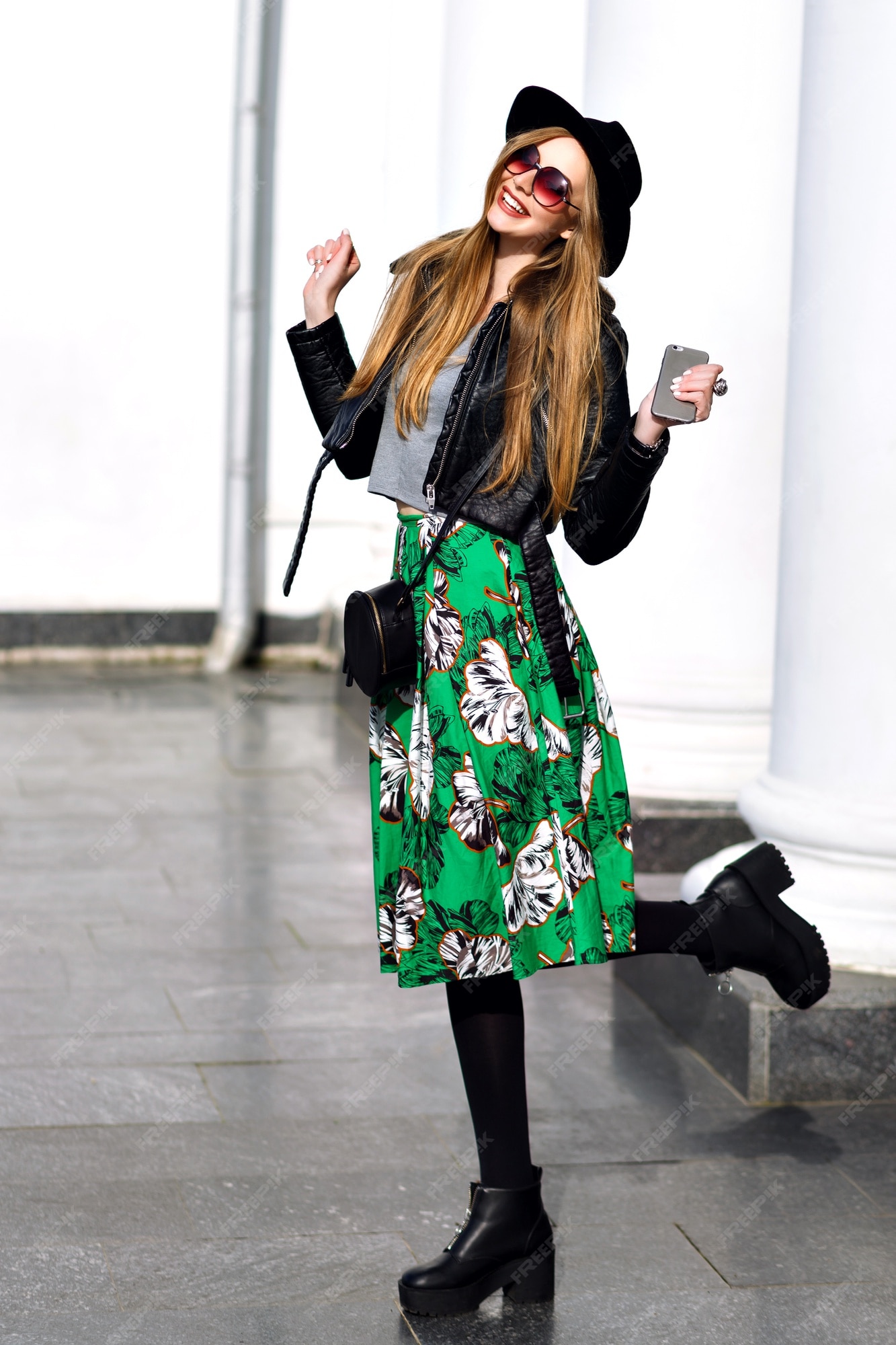 Feliz primavera soleada de una mujer joven y bonita con cabello largo morena con sombrero, falda verde larga, tacones caminando en la calle. de moda, expresando emociones positivas a la cámara,