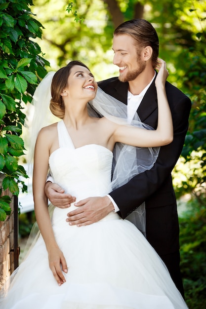 Feliz recién casados sonriendo, mirando el uno al otro en el parque.