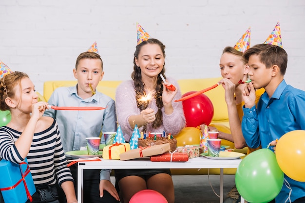 Feliz retrato de una adolescente sosteniendo un petardo en la mano disfrutando en la fiesta de cumpleaños