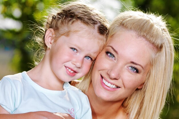 Feliz retrato de joven madre y linda hijita - en la naturaleza