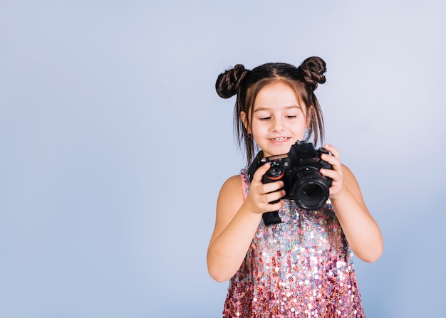 Foto gratuita feliz retrato de una niña mirando a la cámara contra el fondo azul