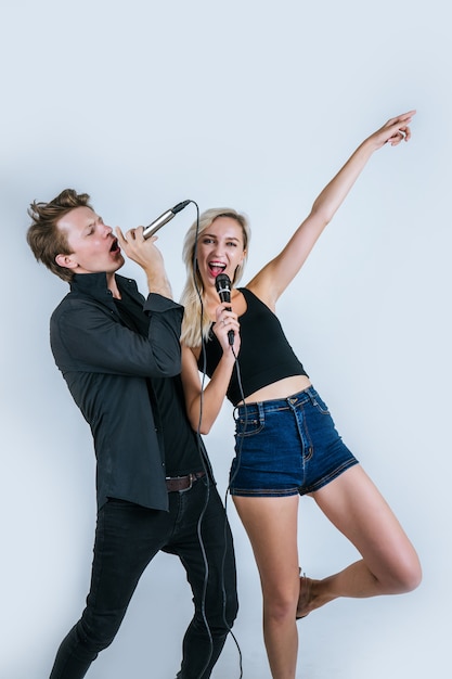 Feliz retrato de pareja con micrófono y canta una canción