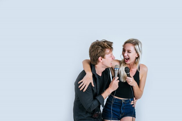 Feliz retrato de pareja con micrófono y canta una canción