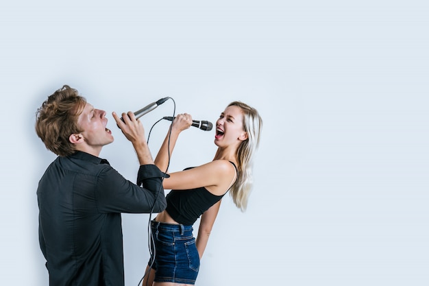 Feliz retrato de pareja con micrófono y canta una canción