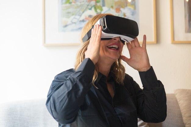Feliz rubia emocionada disfrutando de la experiencia de realidad virtual en casa