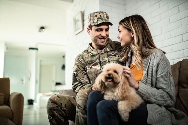 Feliz soldado del ejército y su esposa comunicándose mientras se relaja en casa con su perro