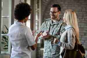 Foto gratuita feliz soldado del ejército y su esposa comunicándose con un trabajador de la salud afroamericano mientras consultan en la clínica