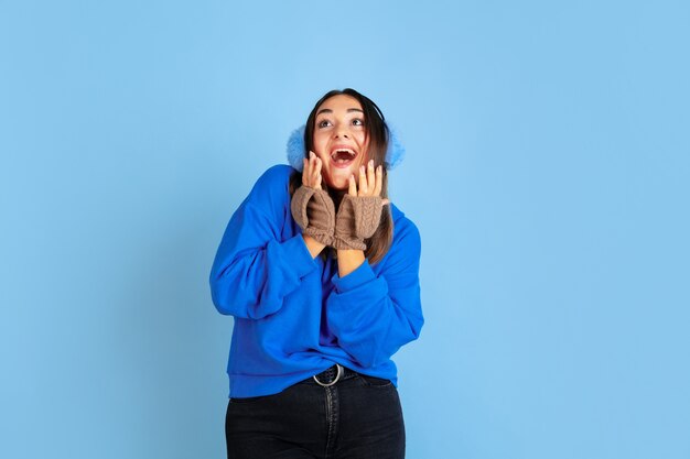 Feliz sonriendo. Retrato de mujer caucásica sobre fondo azul de estudio. Modelo de mujer hermosa en ropa de abrigo. Concepto de emociones, expresión facial, ventas, publicidad. Estado de ánimo de invierno, Navidad, vacaciones.