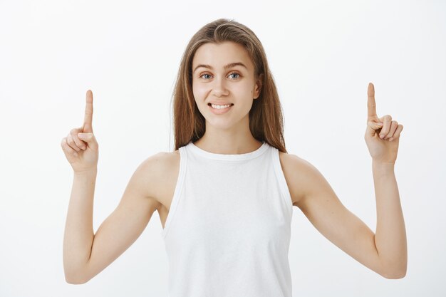 Feliz sonriente, atractiva chica apuntando con el dedo hacia arriba y banner