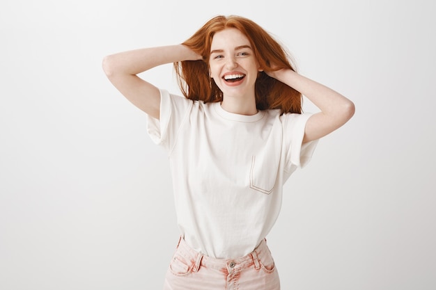 Feliz sonriente, elegante pelirroja tocando su cabello