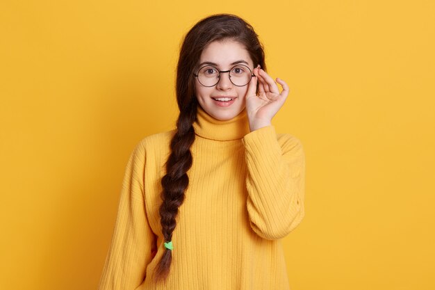 Feliz sonriente emocionada joven con coleta con camisa amarilla