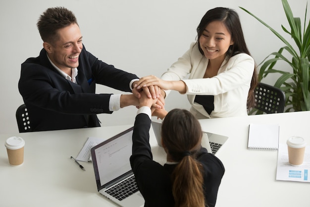 Feliz sonriente equipo diverso unir las manos en la reunión del grupo