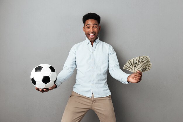 Feliz sonriente hombre africano con billetes de fútbol y dinero