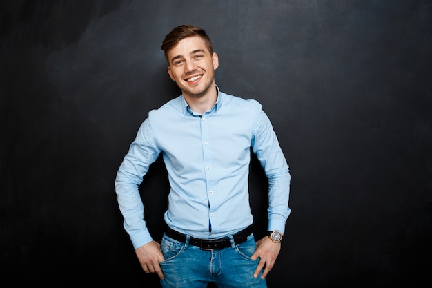 feliz sonriente joven en camisa azul sobre pizarra