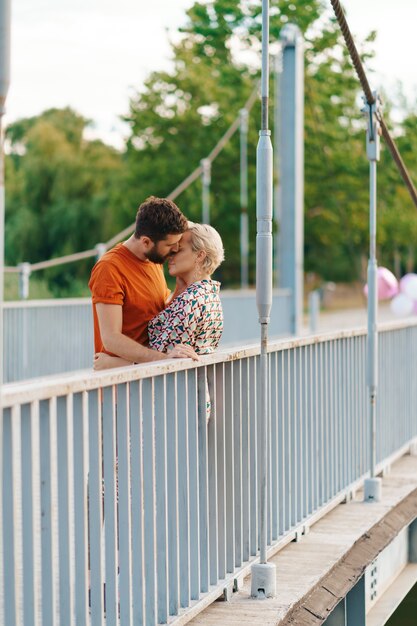 Feliz sonriente joven pareja abrazándose y besándose en el puente