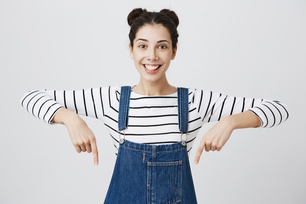 Feliz sonriente mujer adolescente jadeando, apuntando hacia abajo