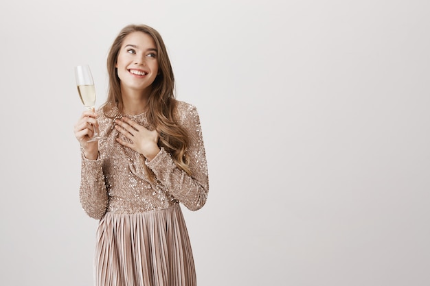 Feliz sonriente mujer en vestido de noche bebiendo champán