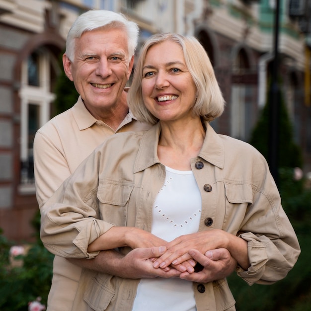 Feliz y sonriente pareja de ancianos posando juntos mientras da un paseo por la ciudad