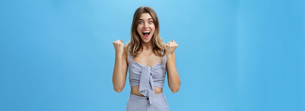 Foto gratuita feliz, sorprendida y triunfante, joven y bonita con el peinado natural ondulado a la par de las rayas.