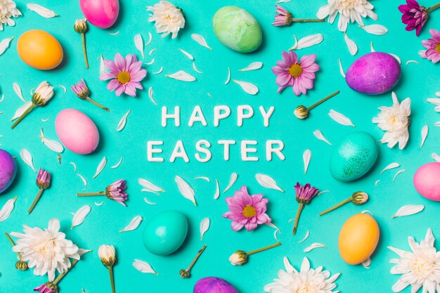 Feliz título de Pascua entre huevos brillantes y capullos de flores.