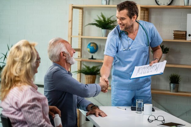 Feliz trabajador de la salud y pareja madura saludando en su oficina Los hombres se dan la mano