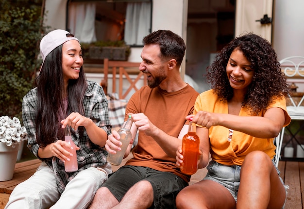 Foto gratuita feliz tres amigos abriendo sus bebidas vista frontal