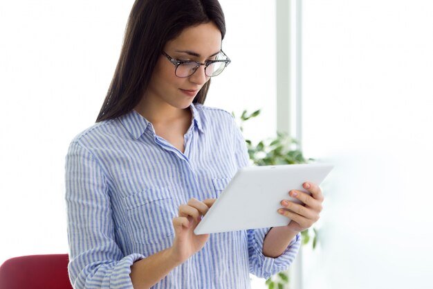 femenino joven en vidrios usando la computadora portátil